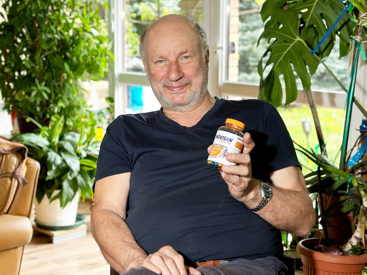 Natural Pharmaceuticals Movisan™ Collagen II Mężczyzna siedzący w jasnym salonie otoczonym roślinami doniczkowymi, trzymający suplement diety Movisan Collagen II z kolagenem wspierającym stawy.