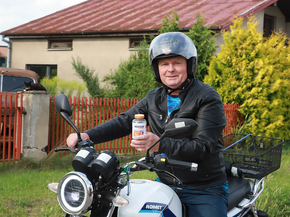 Natural Pharmaceuticals Movisan® Collagen II Mężczyzna siedzący na motocyku trzyma w dłoni butelkę suplementu diety Movisan® Collagen II.